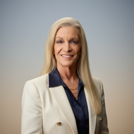 Professional portrait of Theresa Moses Miller a blonde  lady, smiling wearing a white blazer and navy blouse 