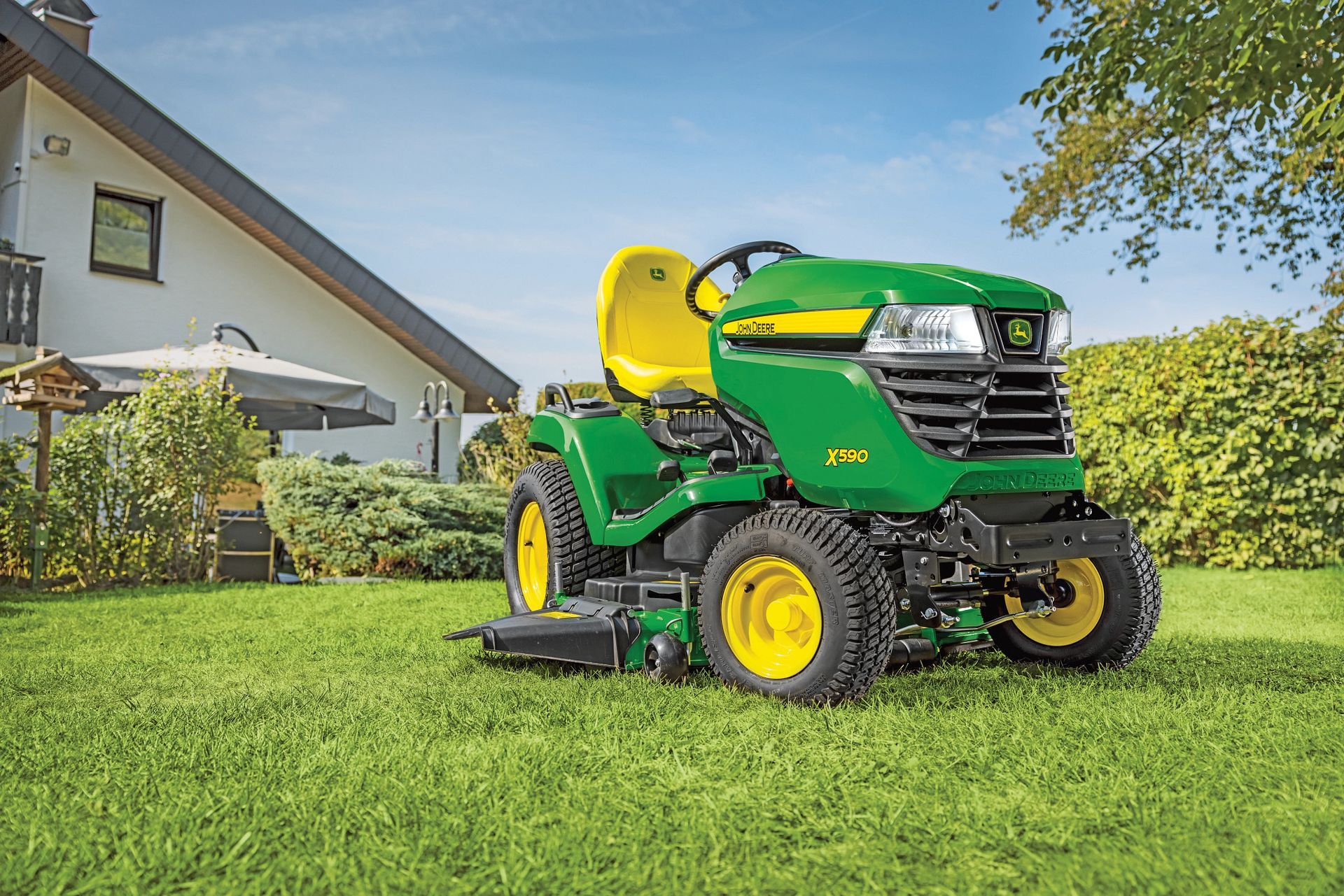 Green John Deere riding lawn mower on grass.