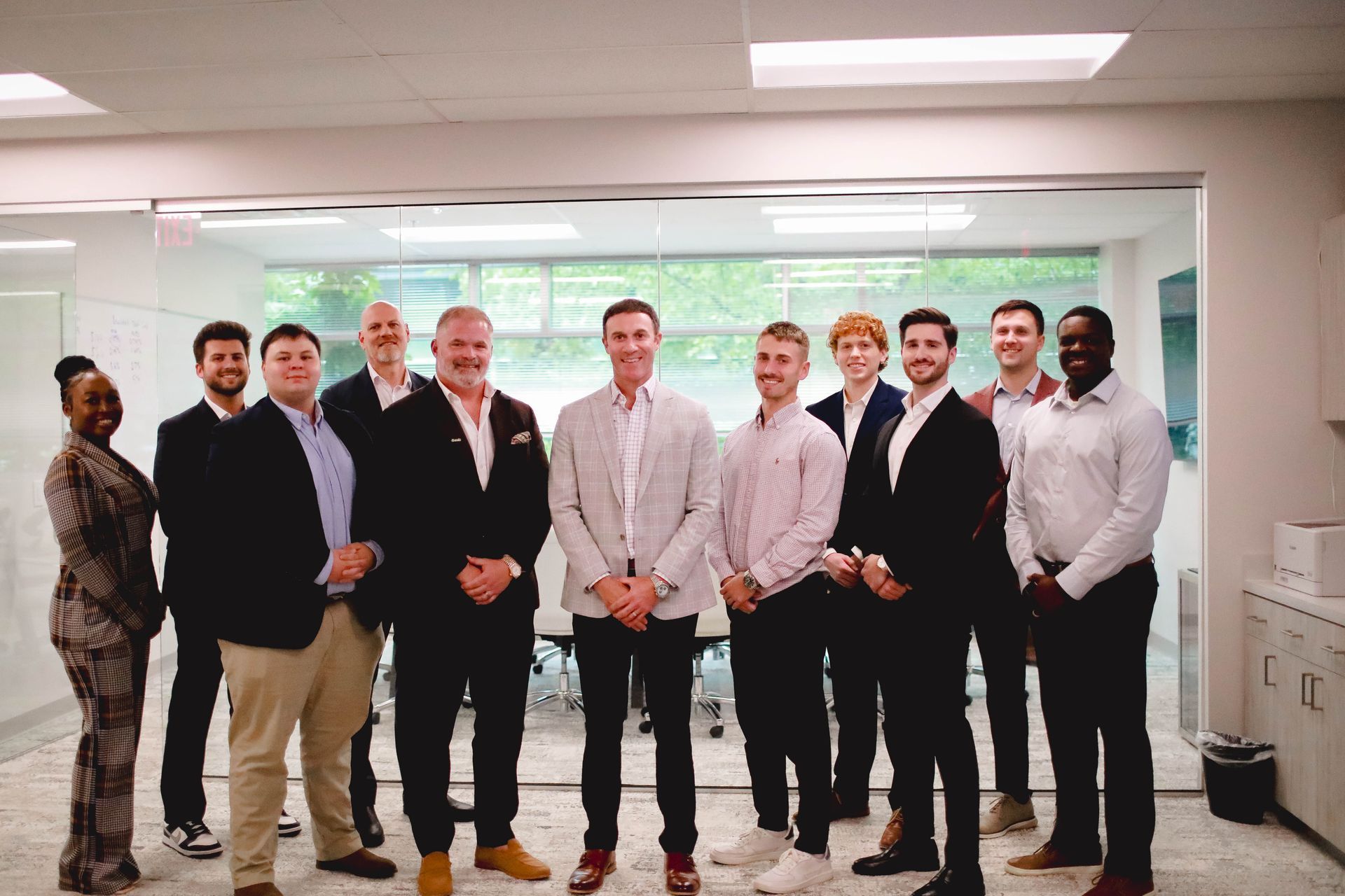 Group of professionals posing in an office lobby, smiling at the camera.