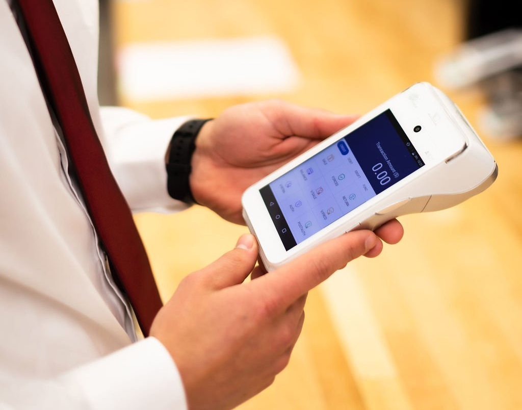 Person using a white smartphone with a payment app on the screen indoors
