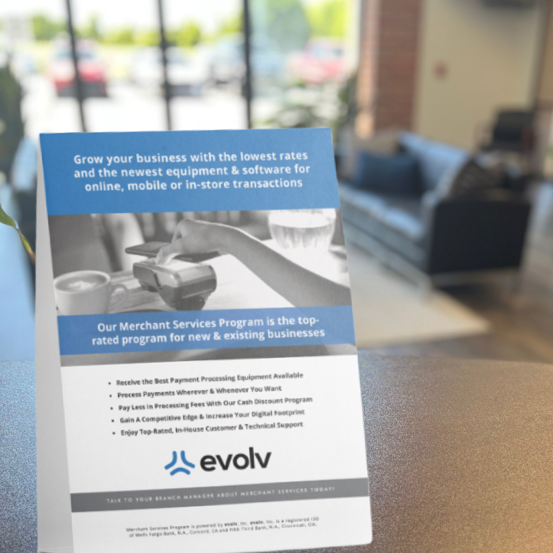 Evolv merchant services flyer on a table, with blue and white text about payment solutions.