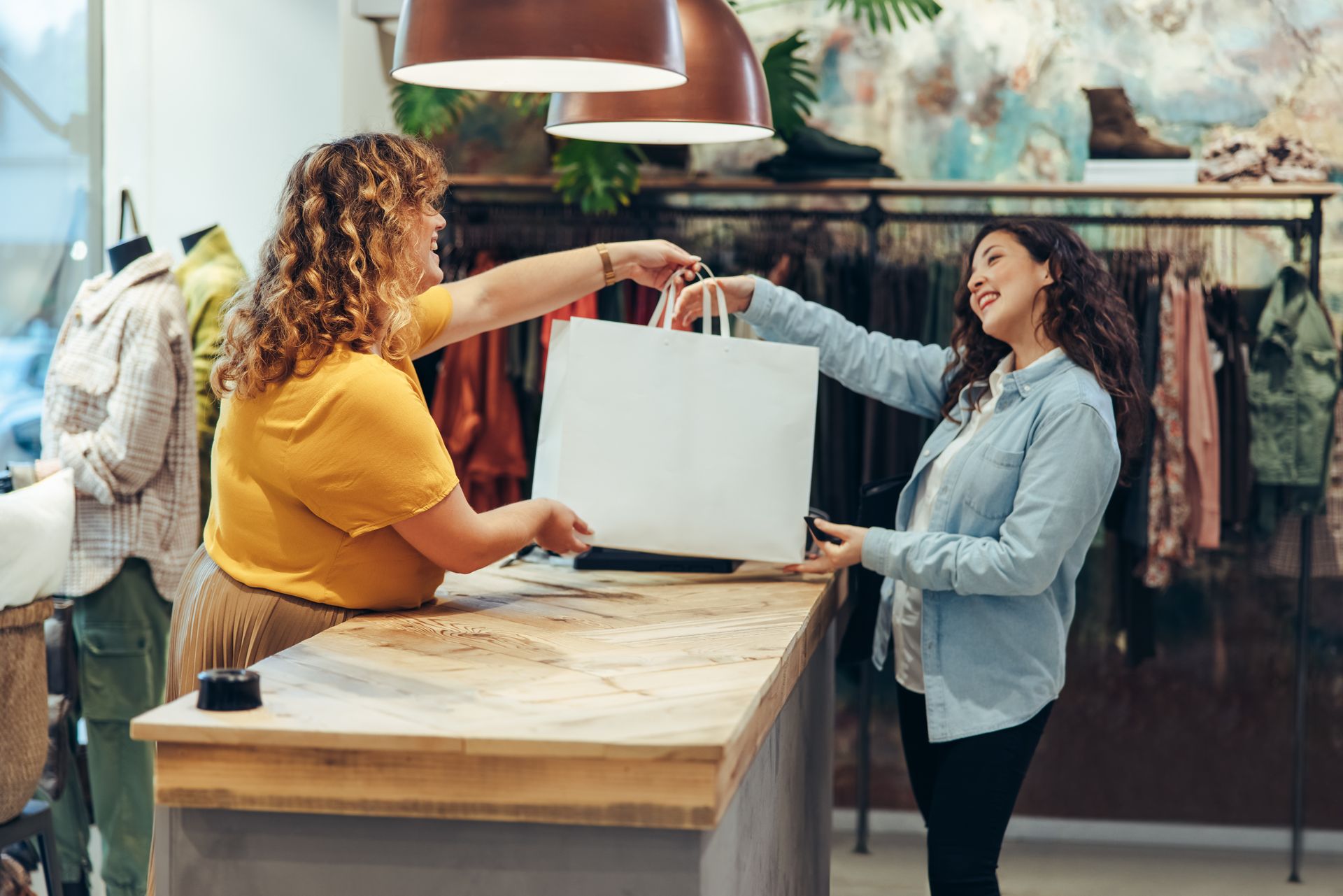 Customer receiving a white shopping bag from a cashier at a boutique counter