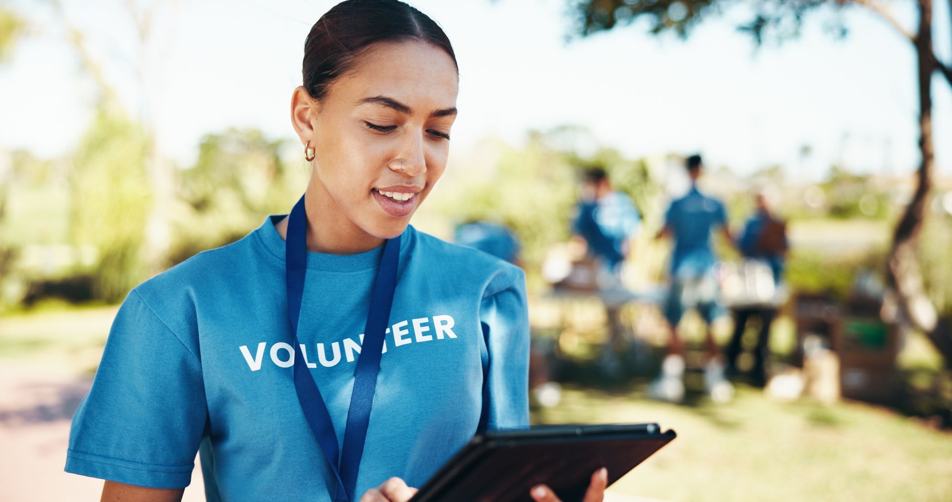 Volunteer in blue shirt using a tablet outdoors at an event