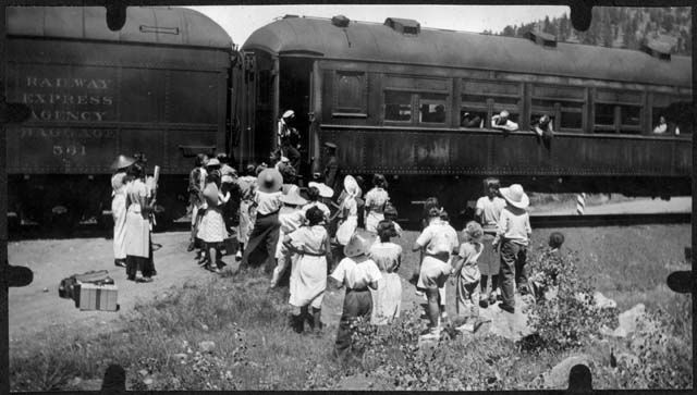 A group of people are standing in front of a train that says railway express agency