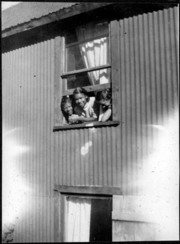 A black and white photo of people looking out of a window