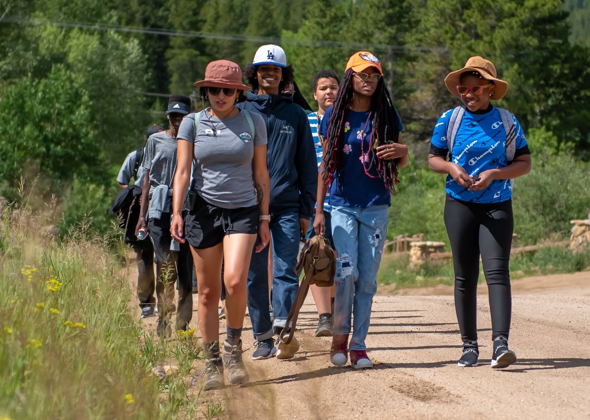A group of people are walking down a dirt road.