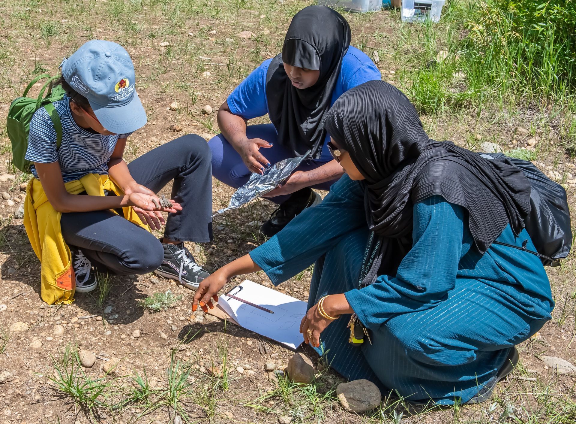 A group of people are sitting on the ground looking at something.