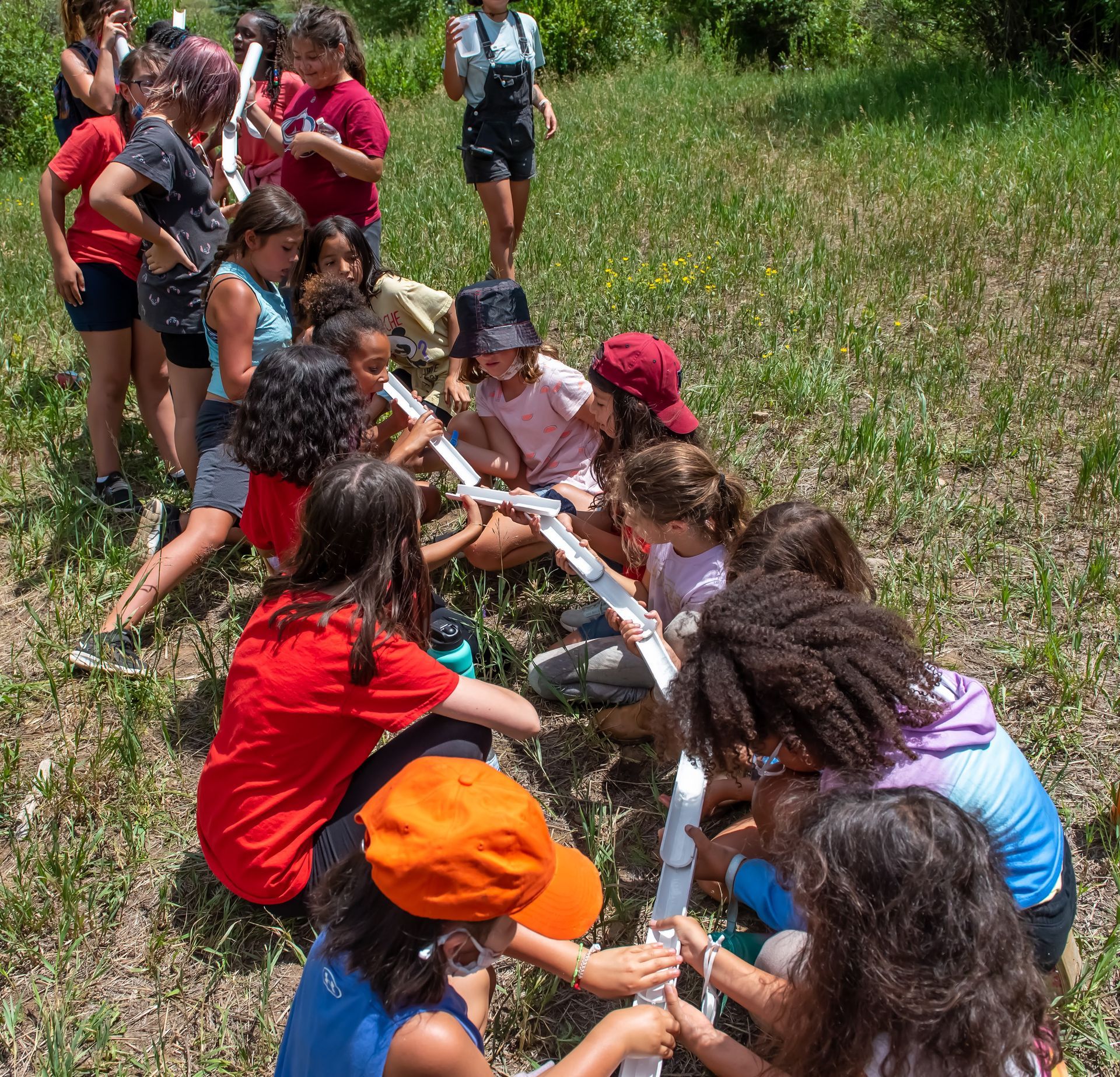 A group of children are sitting in a circle in the grass
