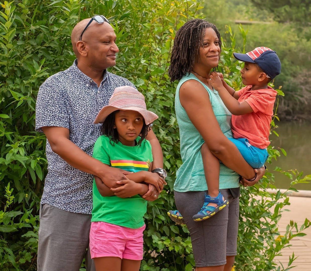 A family is posing for a picture in front of a pond.