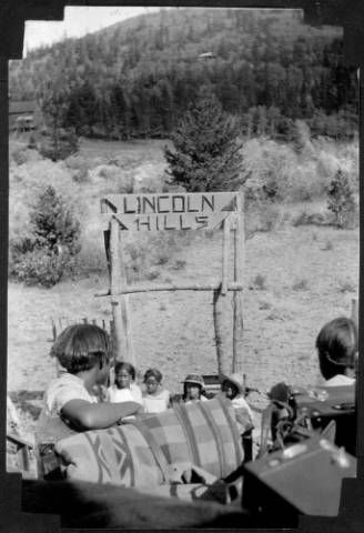 A black and white photo of people in front of a sign that says lincoln hills