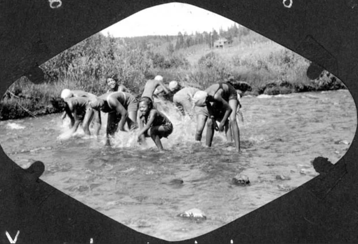 A black and white photo of a group of people in a river