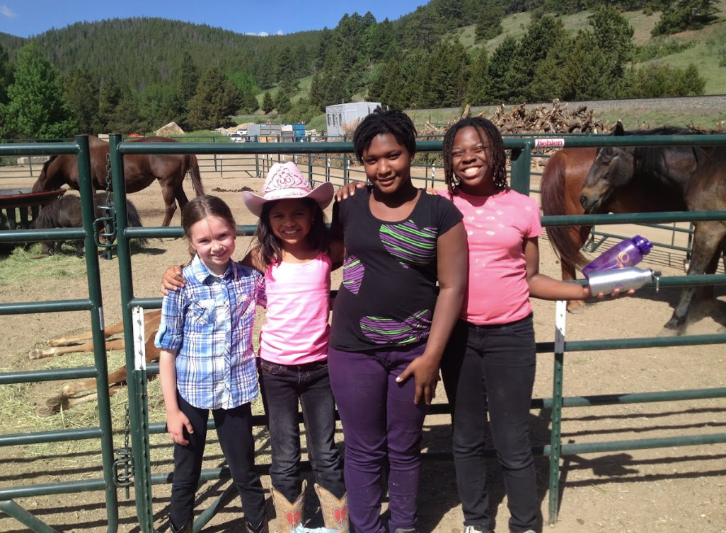 A group of young girls are posing for a picture in front of horses