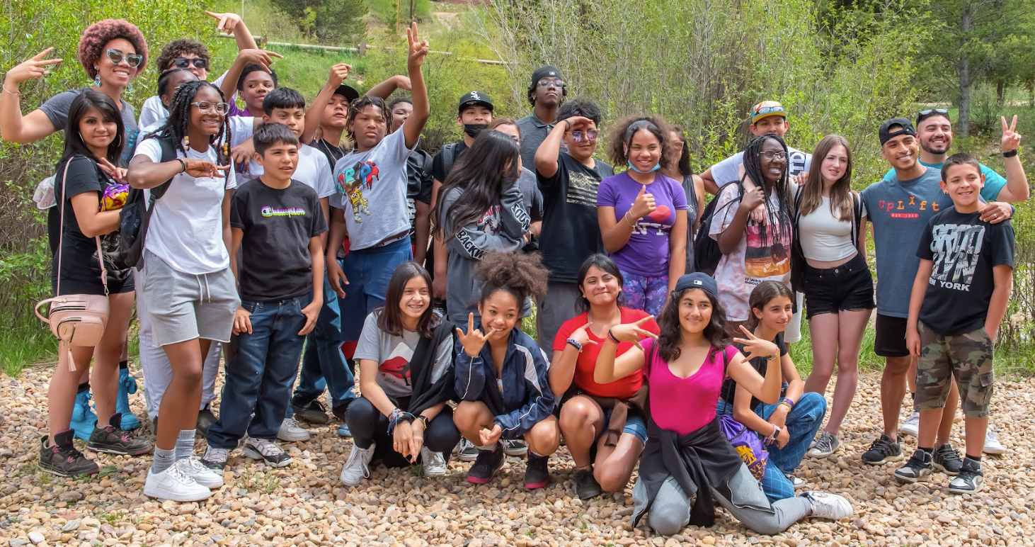 A group of young people are posing for a picture in the woods.