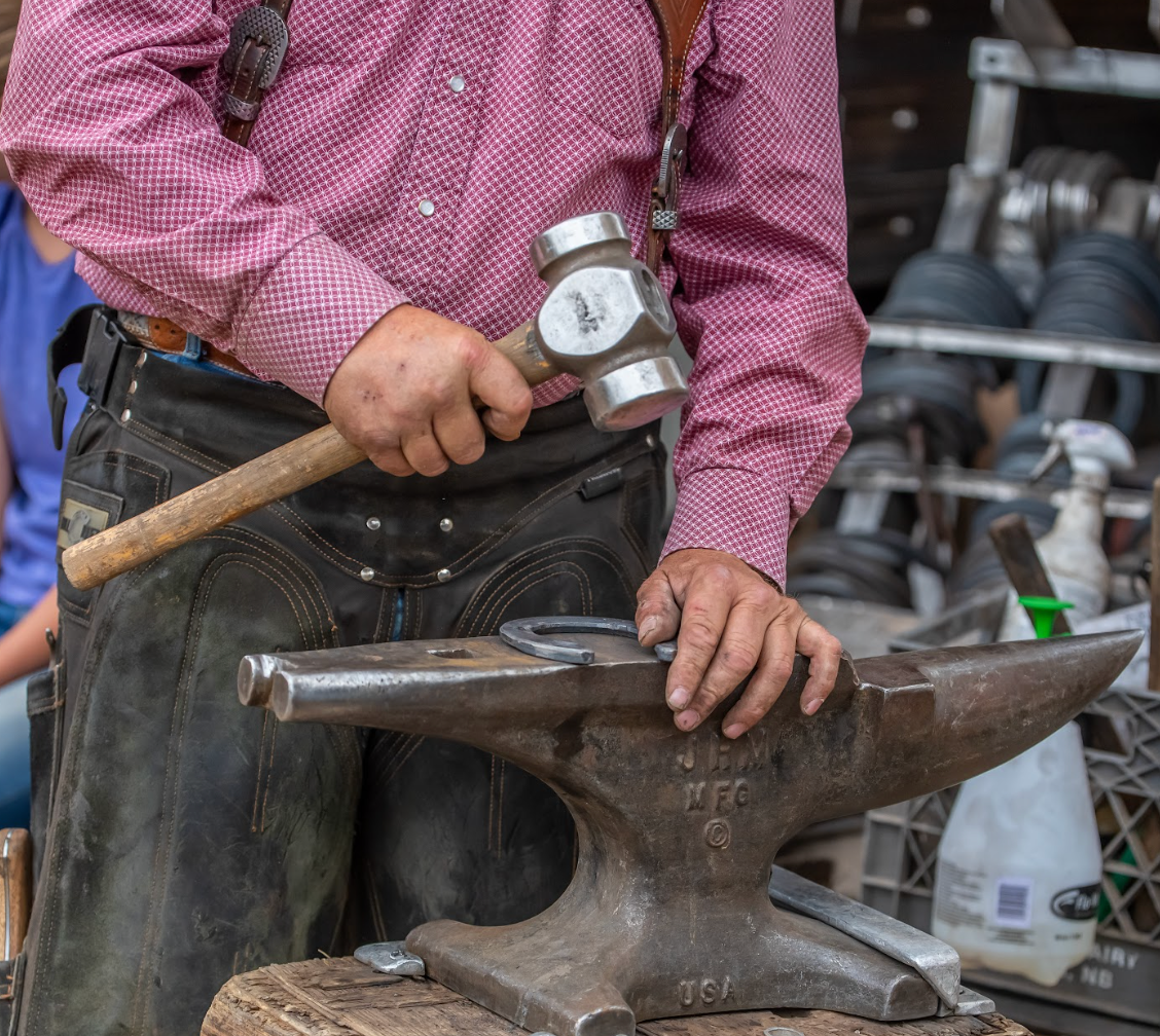 A man is hammering a horseshoe on an anvil