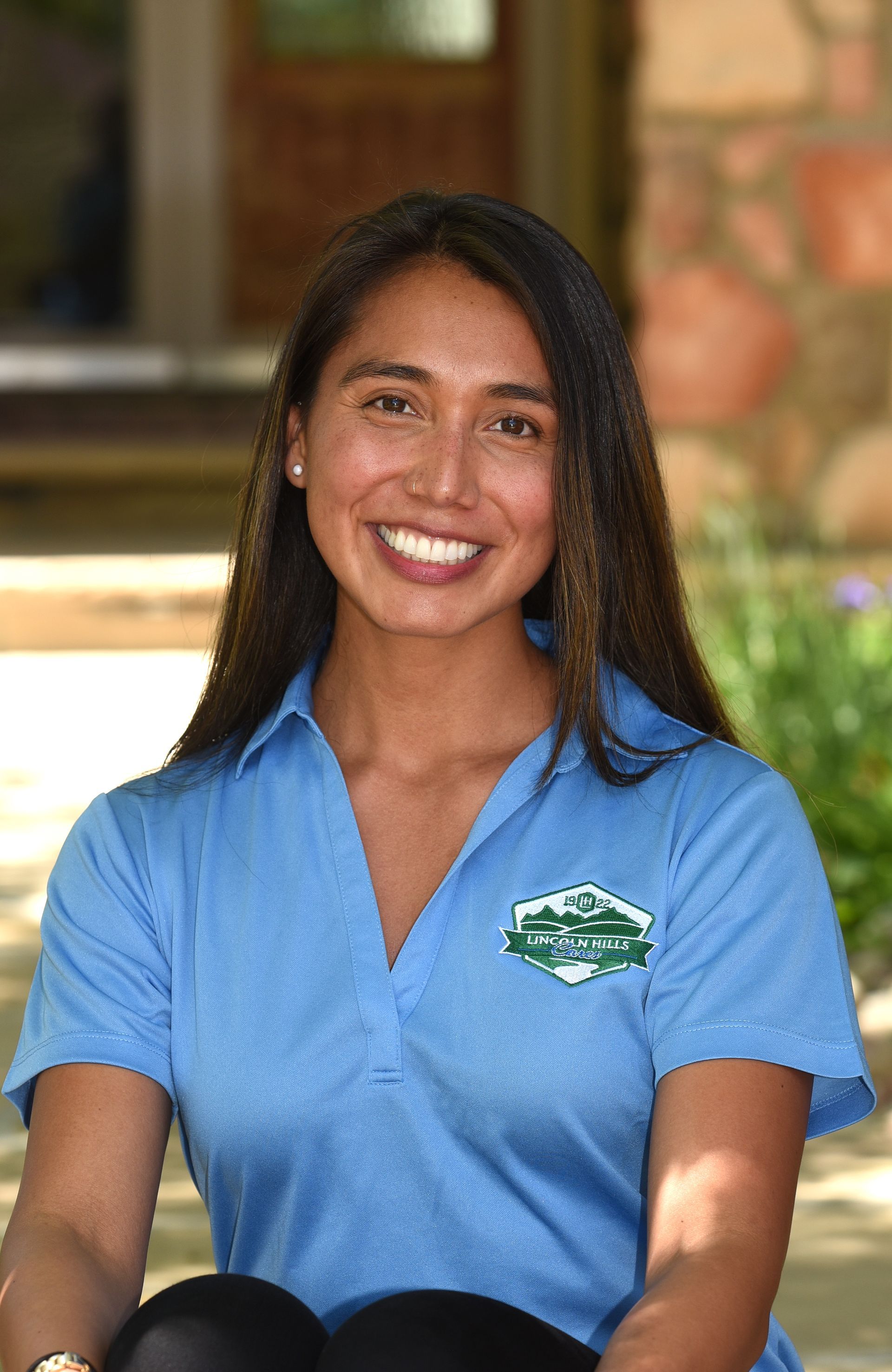 A woman in a blue shirt is smiling for the camera.