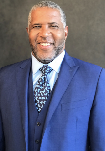 Robert F. Smith wears a navy blue suit and tie as he smiles
