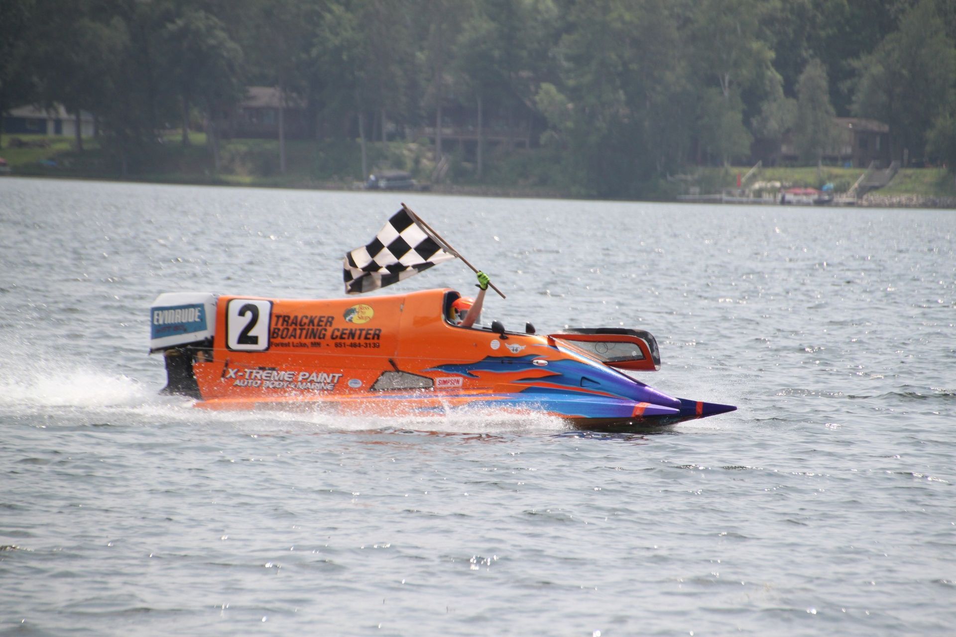 A boat with the number 2 on it is racing on a lake.