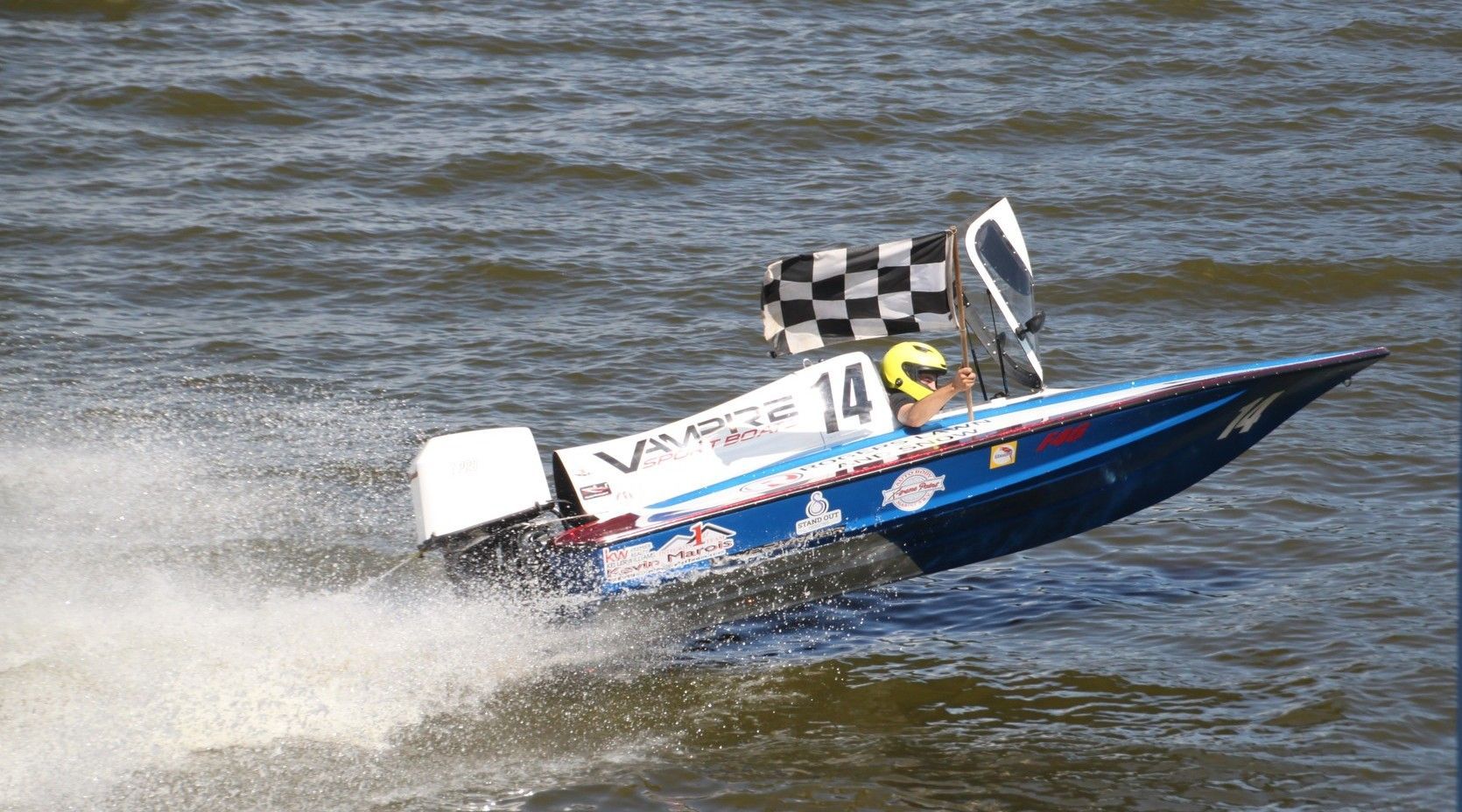 A person is riding a boat in the water with a checkered flag.