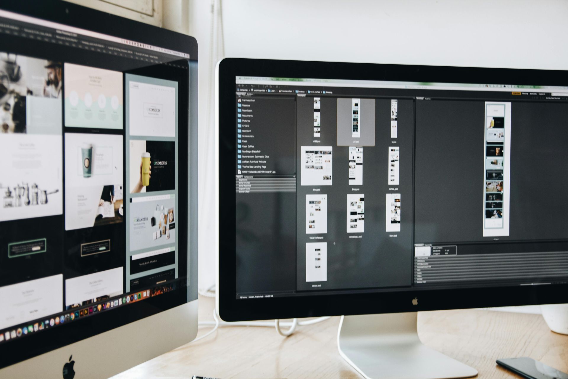 Two computer monitors displaying design work, likely for a website or app, on a desk.
