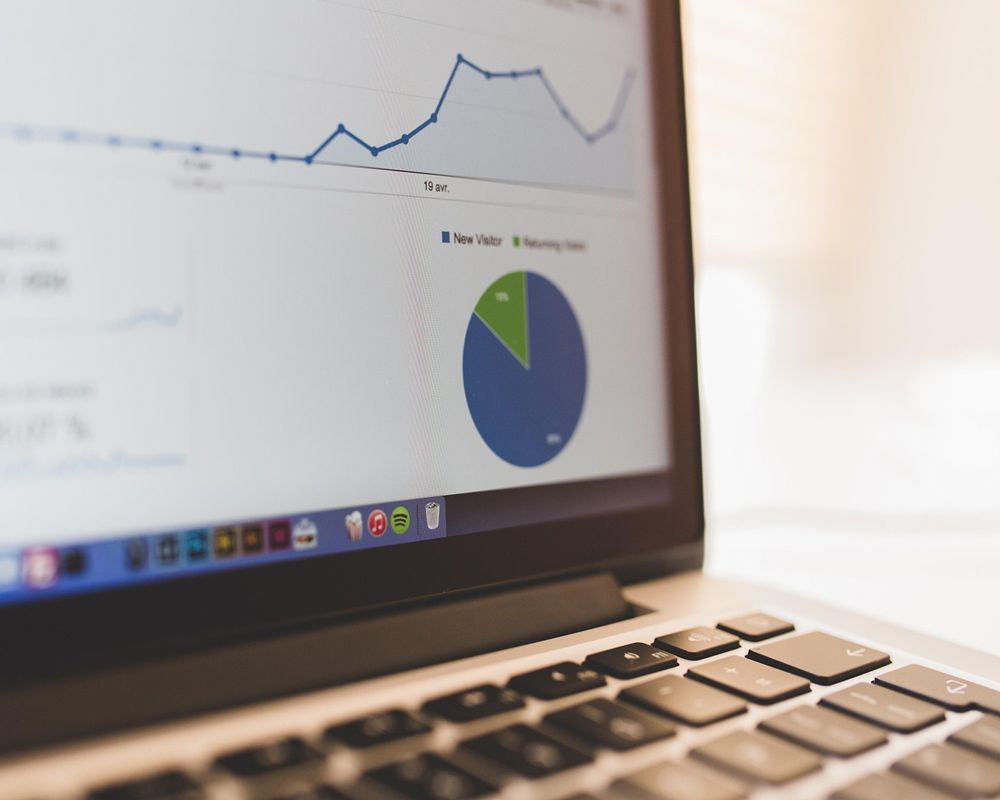 Laptop displaying a line graph and pie chart, likely website analytics.