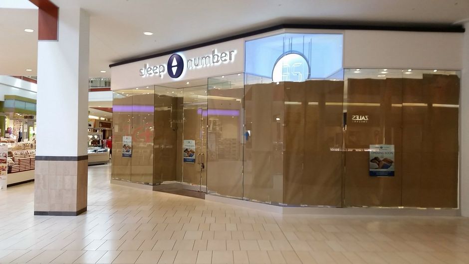 Closed storefront in a shopping mall with reflective glass and wooden panels