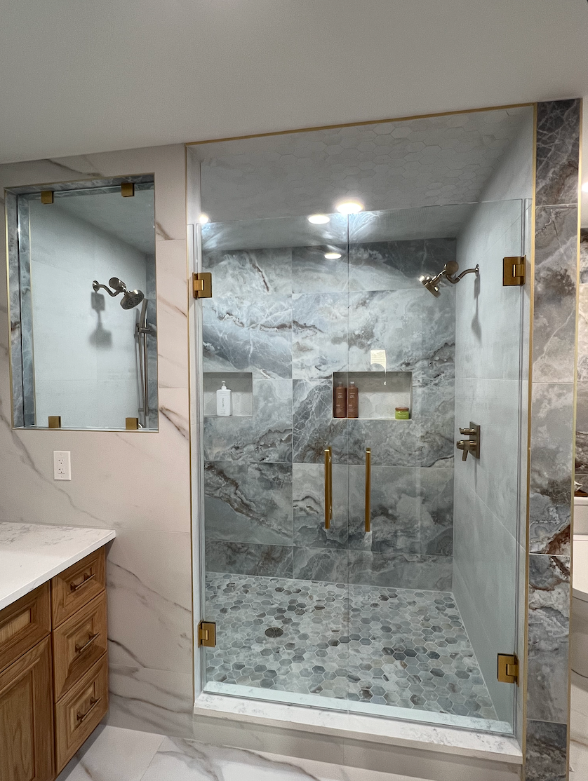 A modern bathroom with a glass shower enclosure and marble tile.