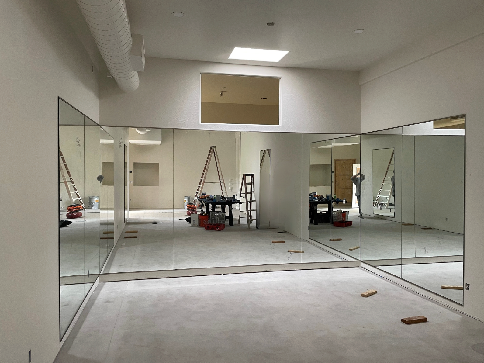 Bathroom with white cabinets, mirror, and a person taking a photo in the mirror.