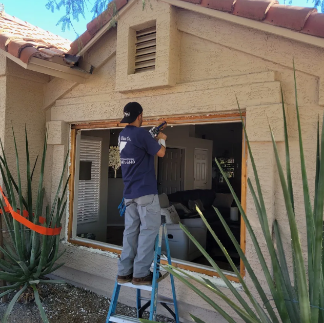 Man inspecting new windows in a wooden-walled room, likely construction site.