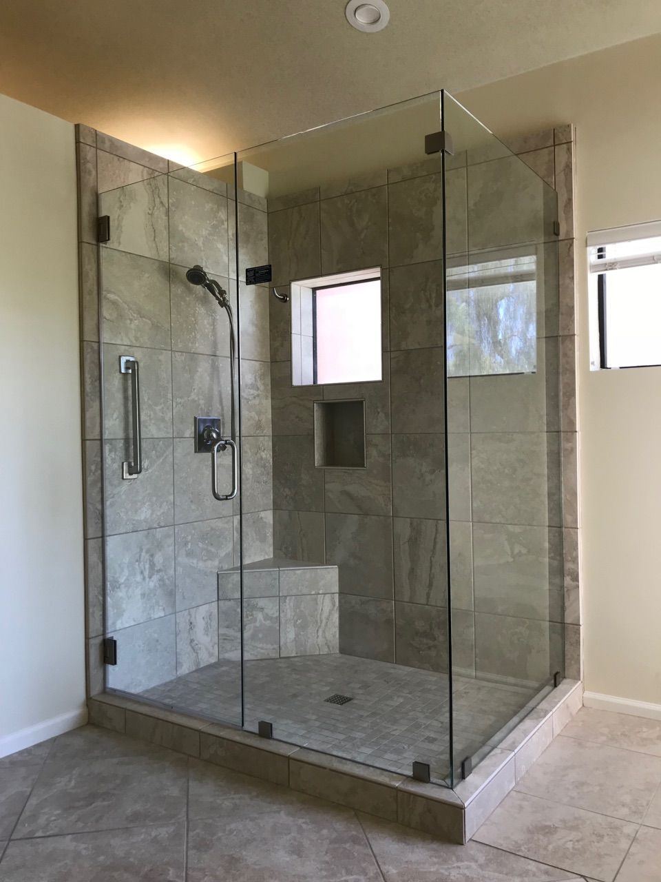 A modern, corner shower with glass walls and tiled interior.