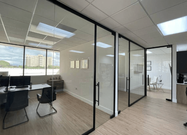 Modern office with glass-walled rooms, natural light, and minimalist decor.