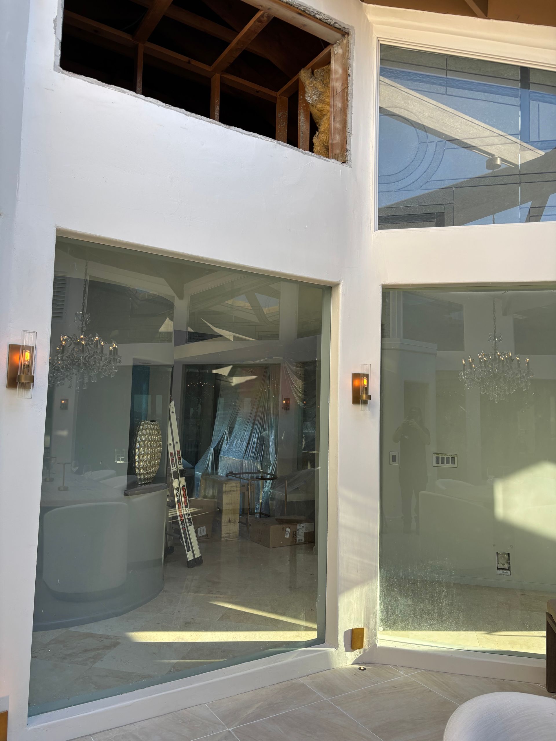 Interior view of a building with large glass windows and white walls, under construction.