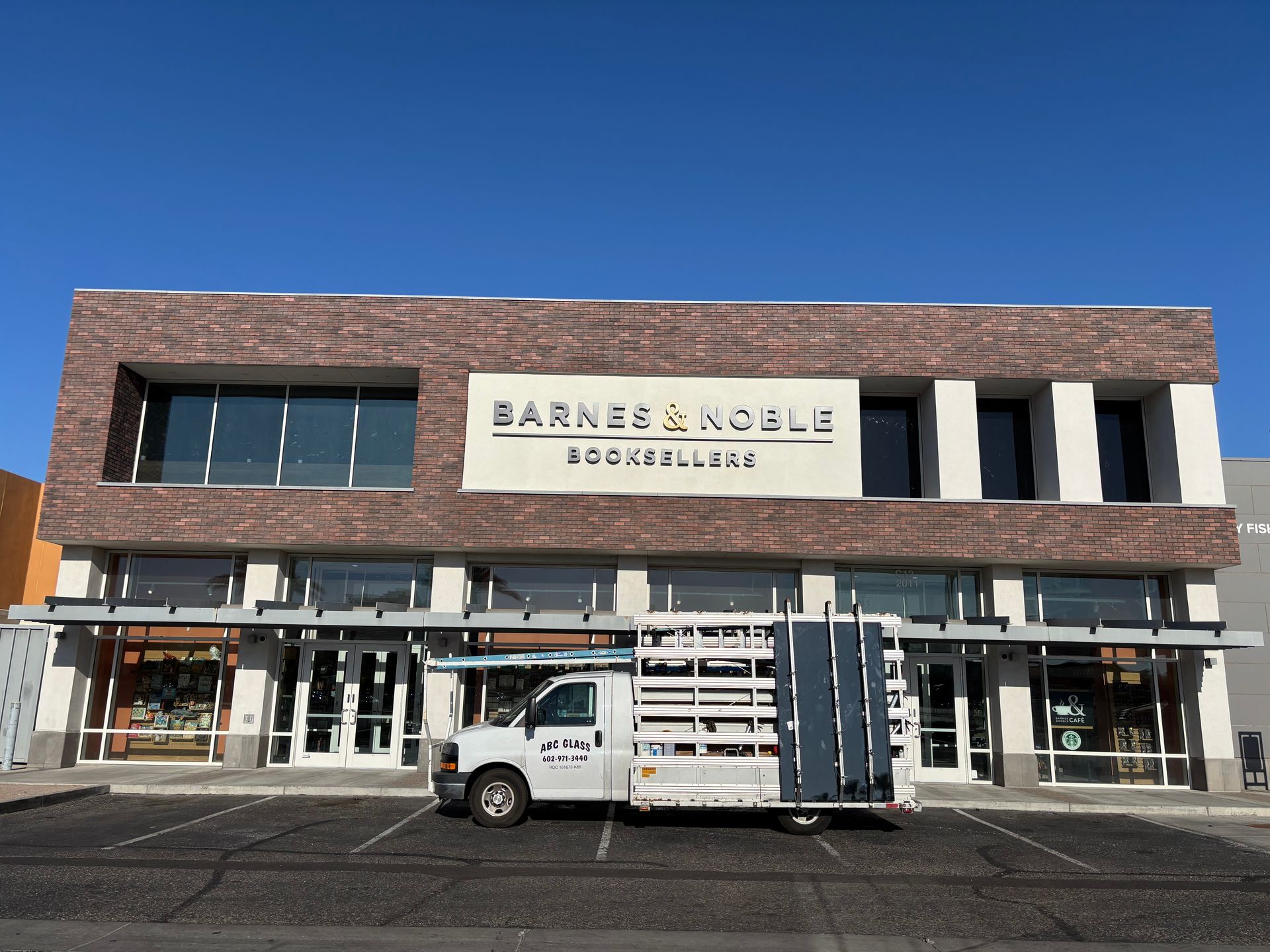 Barnes & Noble bookstore with delivery truck in front. White and brick building, clear sky.