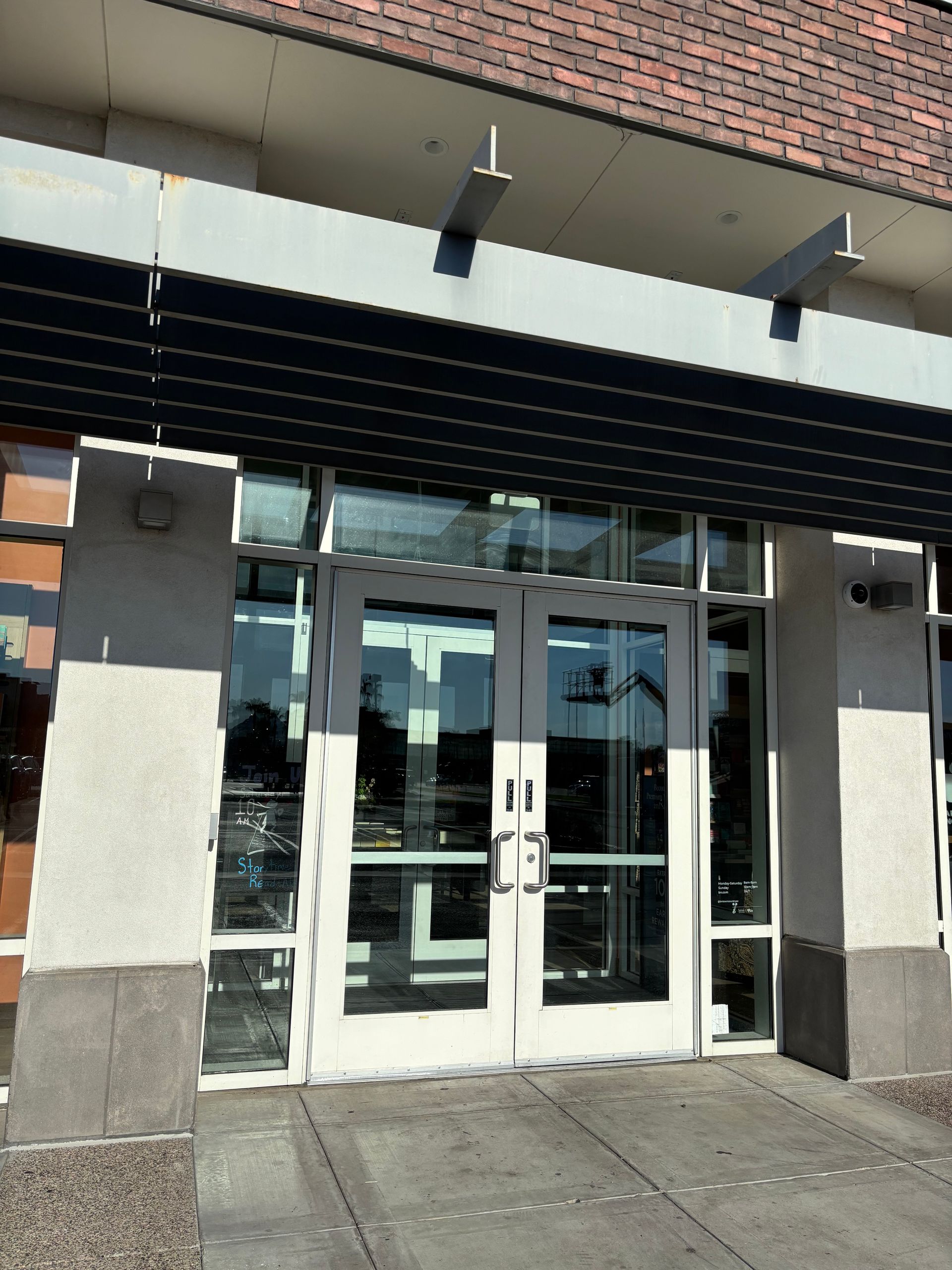 Entrance to a building with glass doors, concrete and brick facade, and awning.