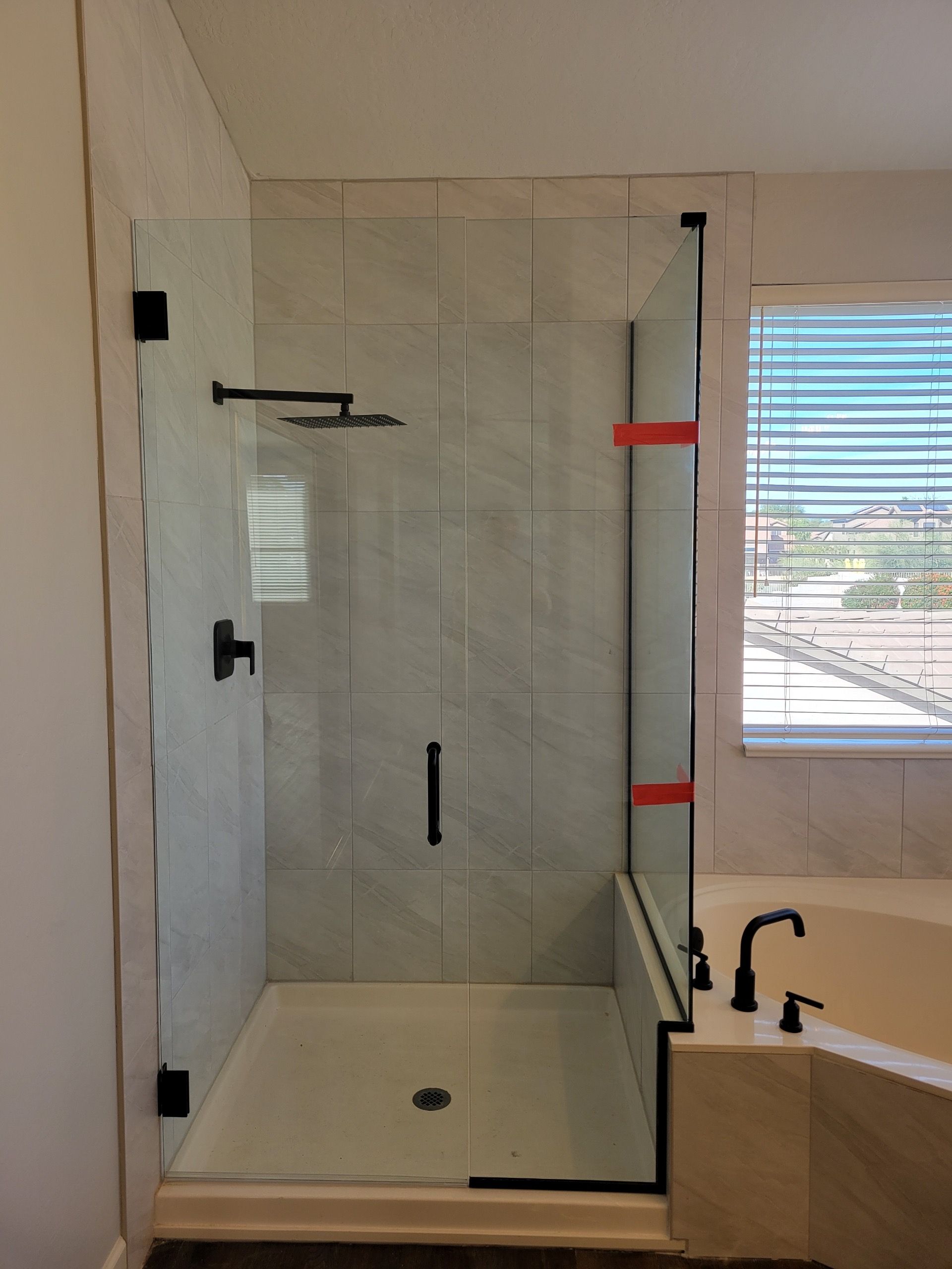 Glass shower enclosure with black fixtures and tile interior in a bathroom.