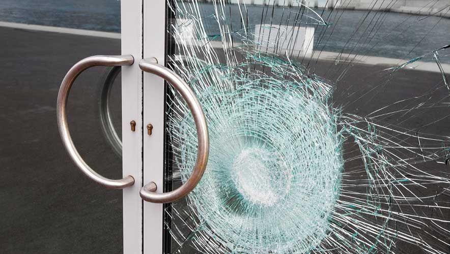 Shattered glass door with a circular break, next to a metal handle.