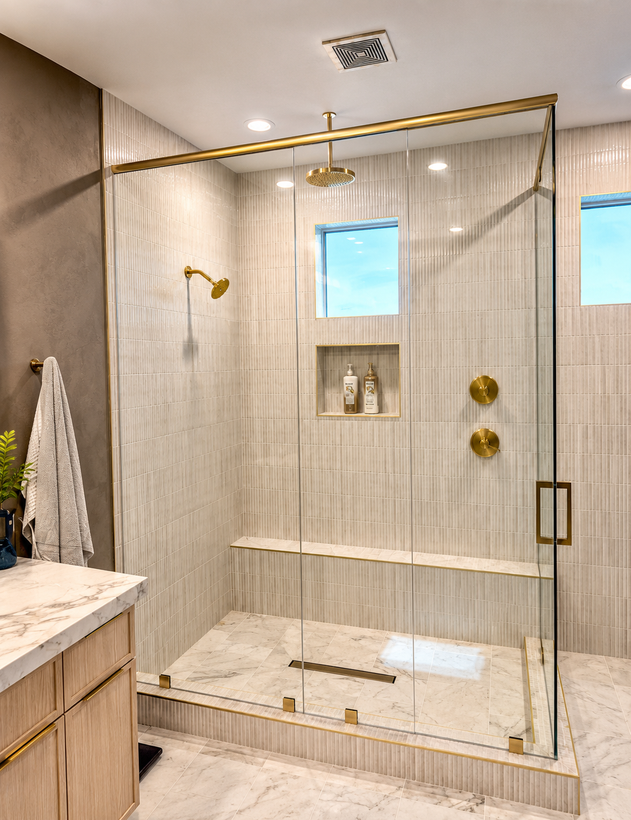 Modern bathroom with a gold-framed glass shower, marble-look tile, and a white vanity.
