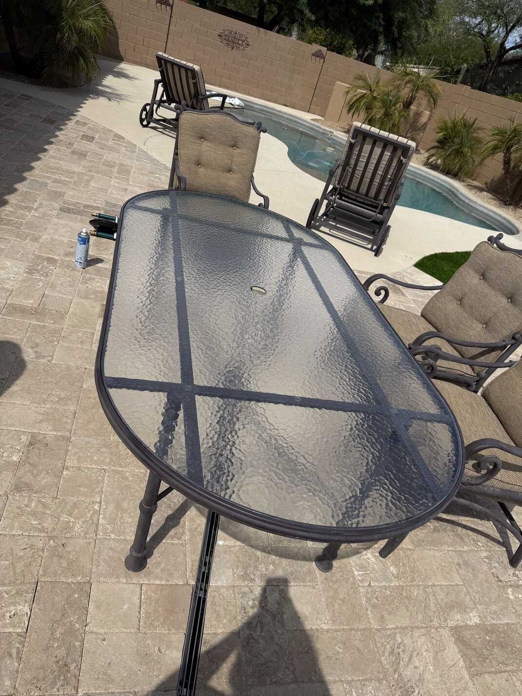 Patio table with chairs, pool in background. Outdoor setting.