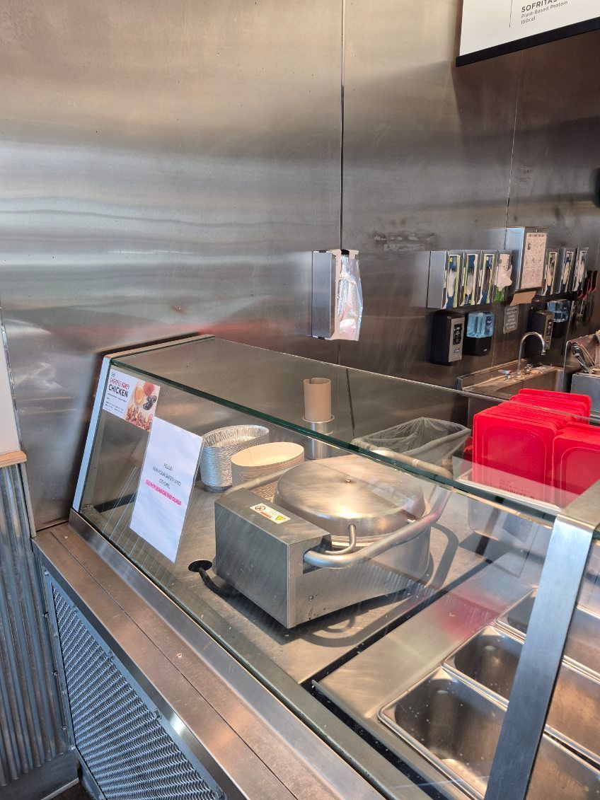 A stainless steel restaurant food prep area with warming equipment behind glass.