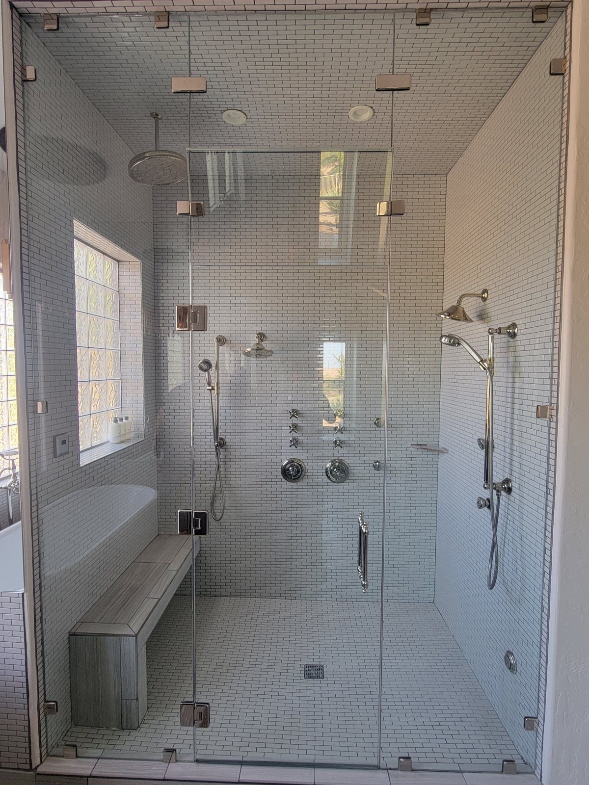 Floor-to-ceiling frameless steam shower glass enclosure with glass top panel, bench and body sprays installed by ABC Glass in Phoenix AZ