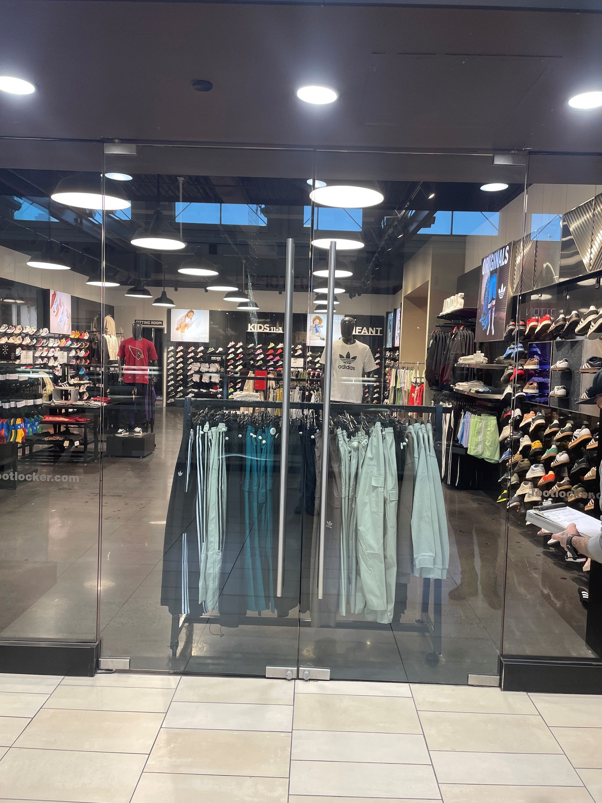 Glass doors open to a clothing store. Clothes racks and shoe displays are visible inside.