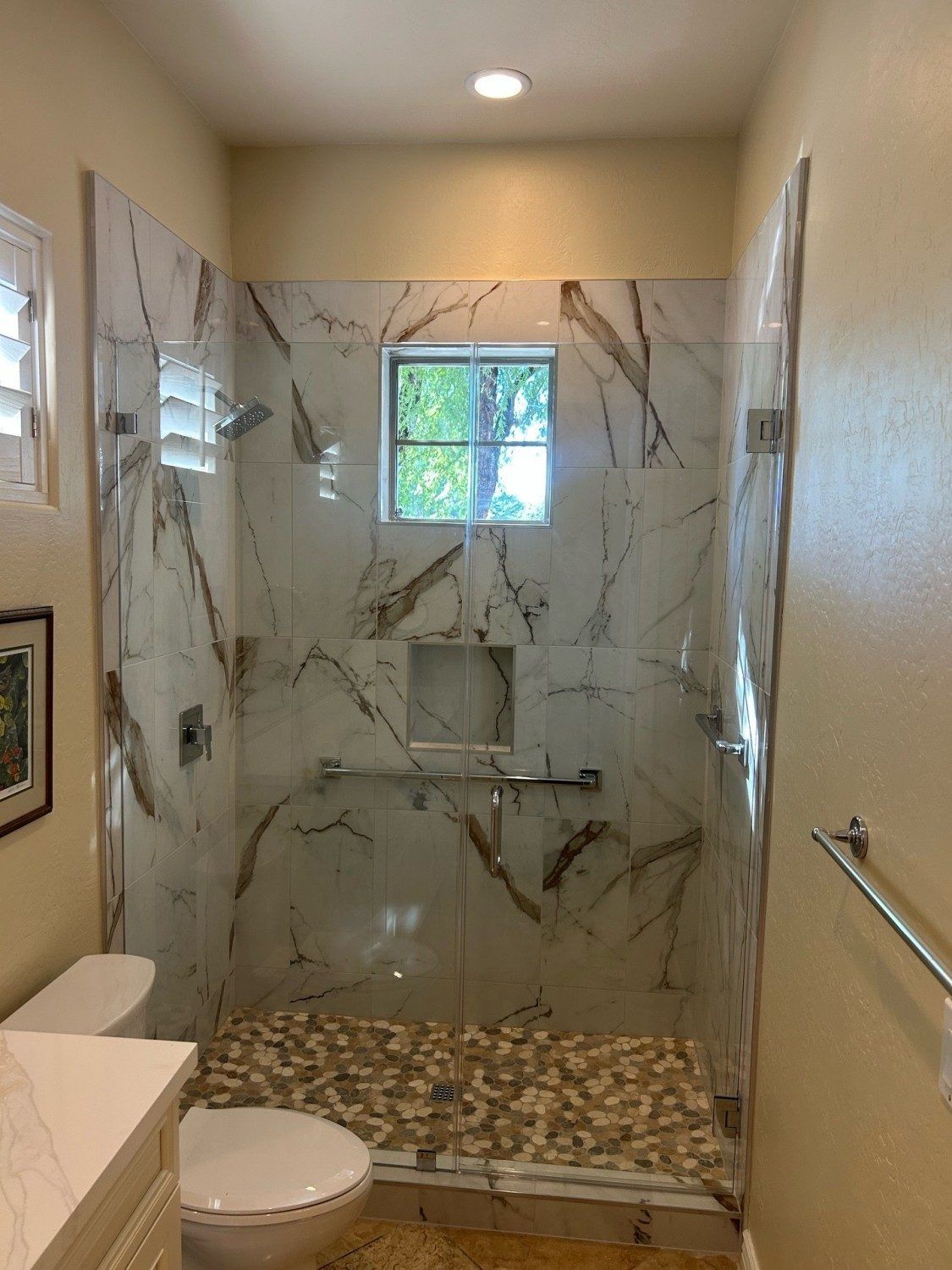 Frameless glass shower door with chrome hardware and white marble tile installed by ABC Glass in Phoenix AZ