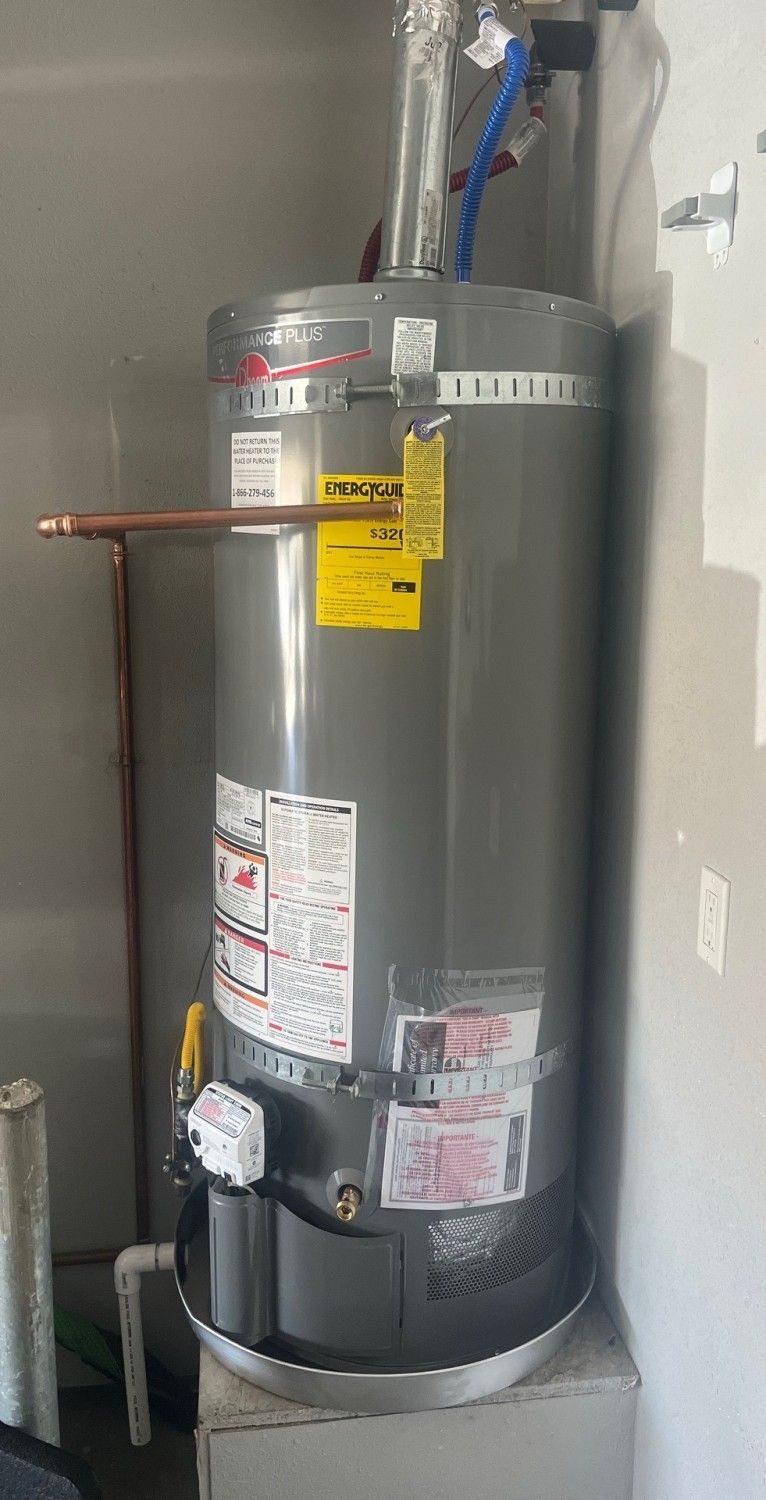 Gray water heater with pipes in a utility closet against a white wall