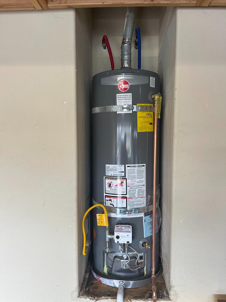 Water heater in a recessed closet with exposed pipes and utility labels