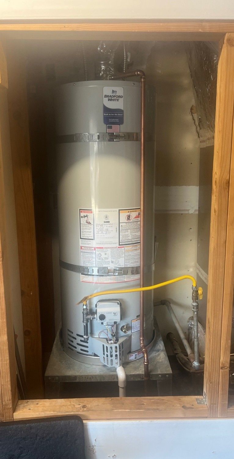 Water heater inside a wooden utility closet, with pipes and wiring visible.