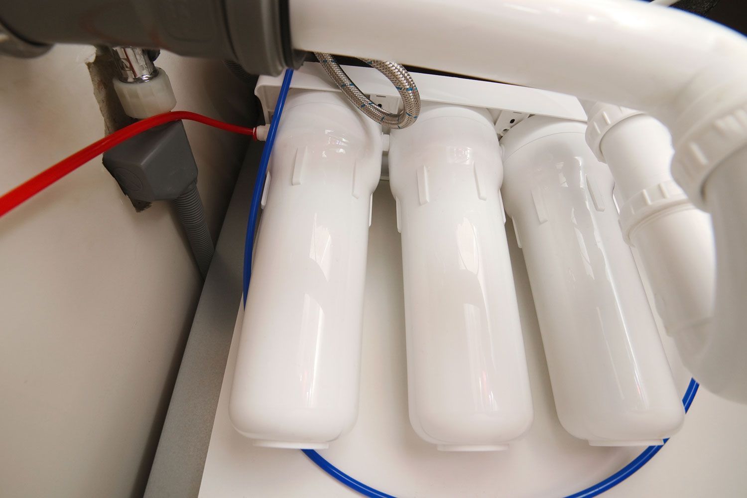 White cylindrical objects connected by red and blue hoses under a white pipe