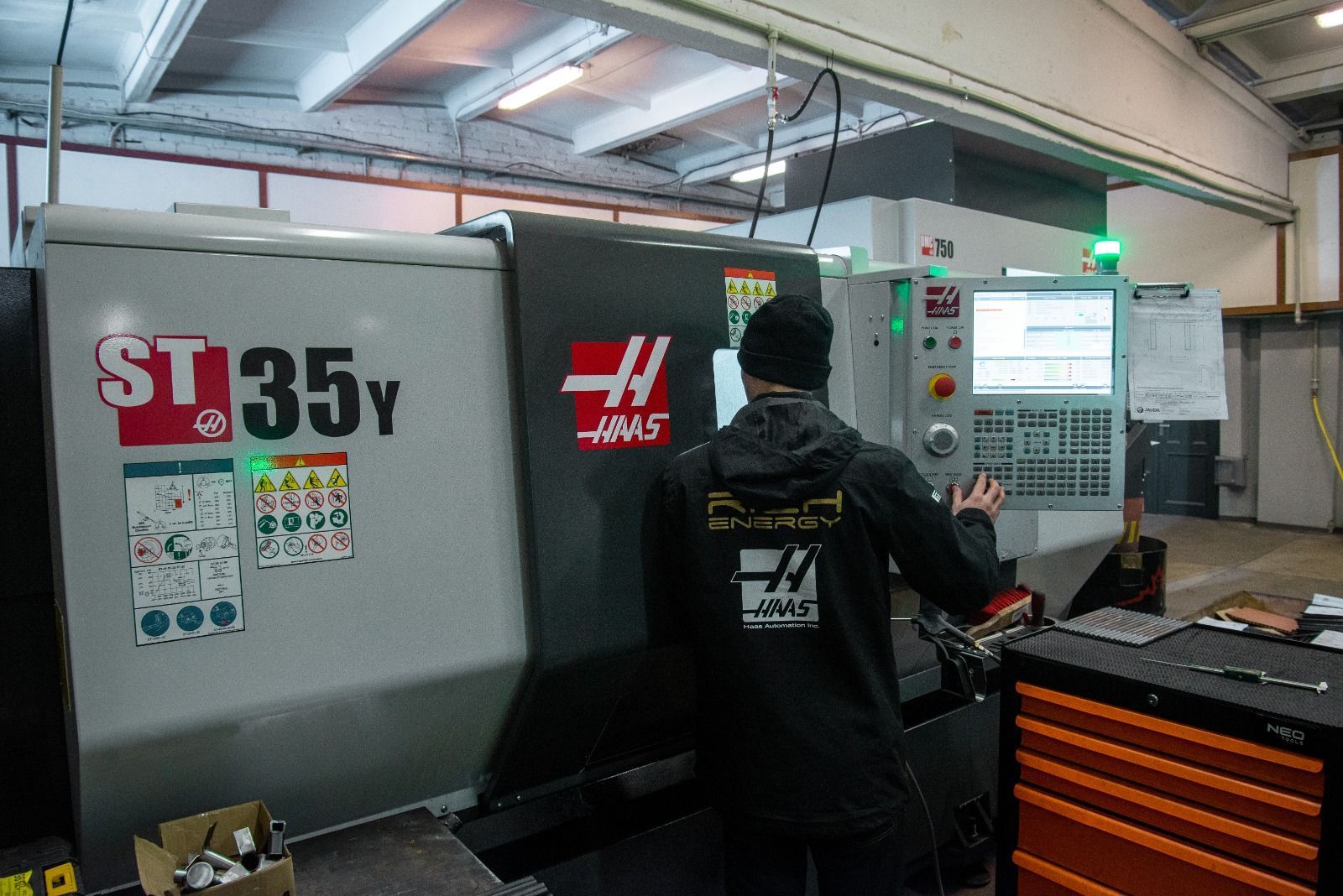 A person operates a Haas ST-35Y CNC machine in a workshop.