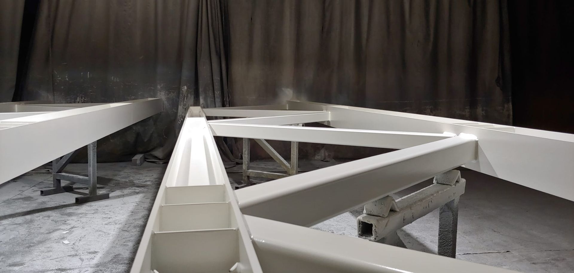 White metal frame being painted in a spray booth.