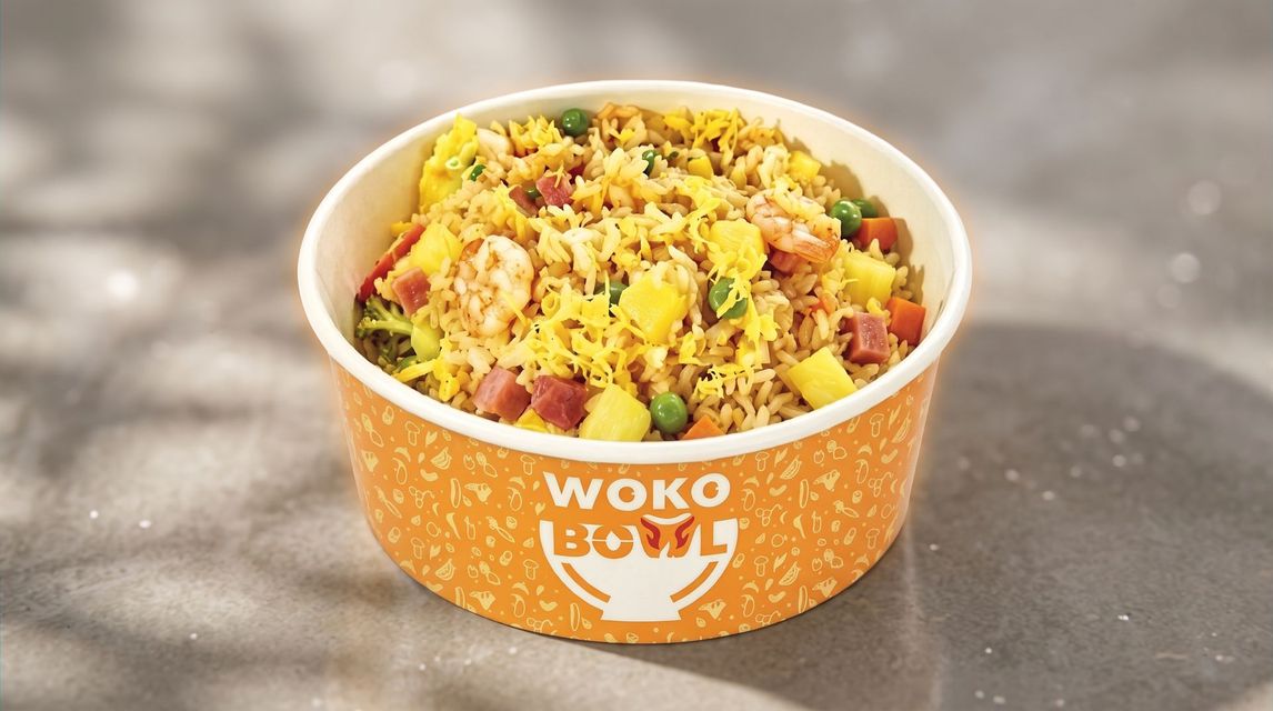 Orange Wok Bowl container filled with colorful fried rice on a blurred outdoor surface
