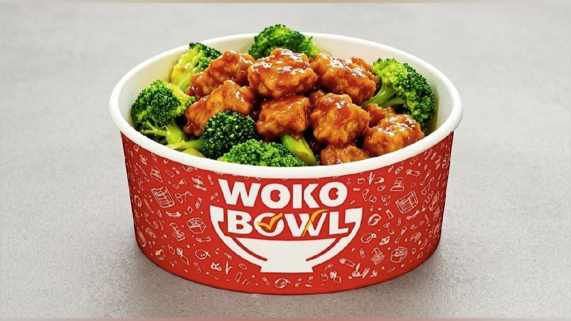 Red WOKO Bowl of orange sauced chicken with broccoli on a gray surface