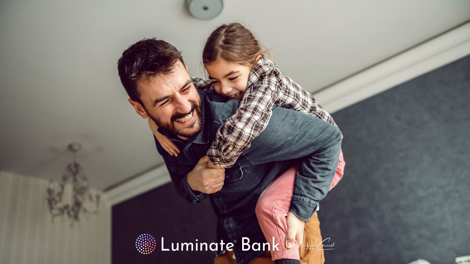 Father and daughter inside a house. Daughter on father's back, both smiling.
